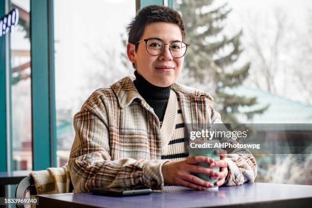comodidad conectada: mensajes de texto profesionales no binarios con café en la cafetería - neurodiversidad fotografías e imágenes de stock