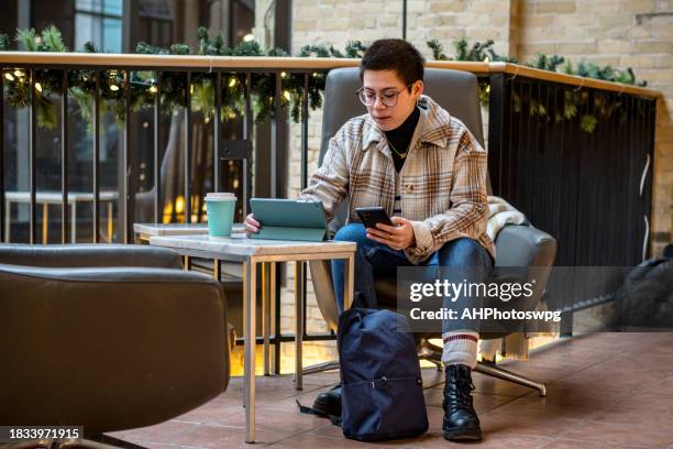 profesional no binario que hace malabares con el teléfono y la tableta con facilidad - neurodiversidad fotografías e imágenes de stock