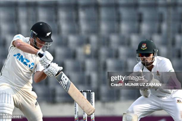 New Zealand's Mitchell Santner plays a shot as the Bangladesh's Nurul Hasan watches during the fourth day of the second Test cricket match between...