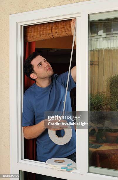 man installs weather stripping in window - uitkleden stockfoto's en -beelden