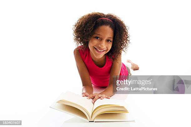 african ethnicity girl lying on front reading book - teenager learning child to read stockfoto's en -beelden