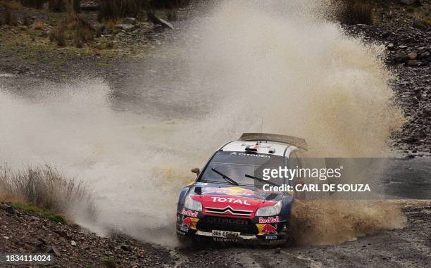 Sebastien Loeb of France and co-driver Daniel Elena of the Citroen Total WRT team navigate a water hazard in their Citroen C4 car during the second...