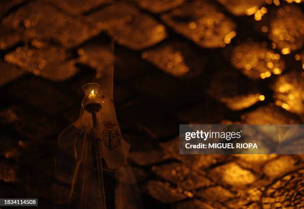 Penitent is seen reflected in a rainwater puddle as he takes part in the 'Cristo del Perdon' brotherhood procession during the Holy Week in Ferrol,...