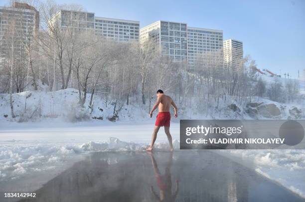 Winter swimming enthusiast stands on the edge of an ice hole at a lake in the Siberian city of Novosibirsk with the air temperature at around minus...