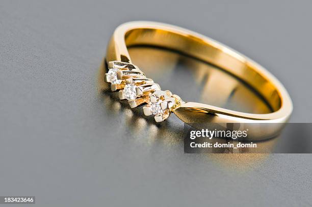 nahaufnahme von einem goldenen ring mit diamanten gegen solid grey - ring schmuck stock-fotos und bilder
