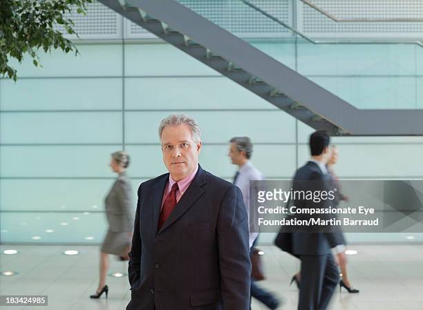 calm businessman standing in busy lobby - 40 50 business woman stock pictures, royalty-free photos & images