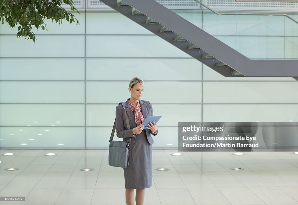 Businesswoman using digital tablet in modern lobby