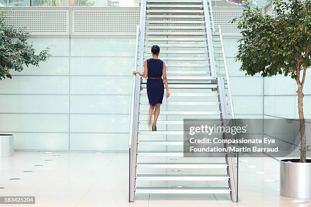 businesswoman in modern lobby, rear view - salire le scale foto e immagini stock