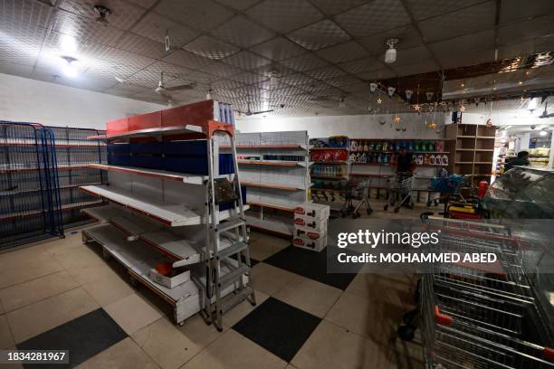 The shelves of a supermarket remain empty apart from cleaning products, in Rafah in the southern Gaza Strip on December 9 amid continuing battles...