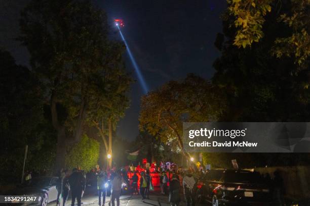 Police helicopter lights up protesters marching in the street to denounce the Biden administration's support of Israel, which has killed thousands of...