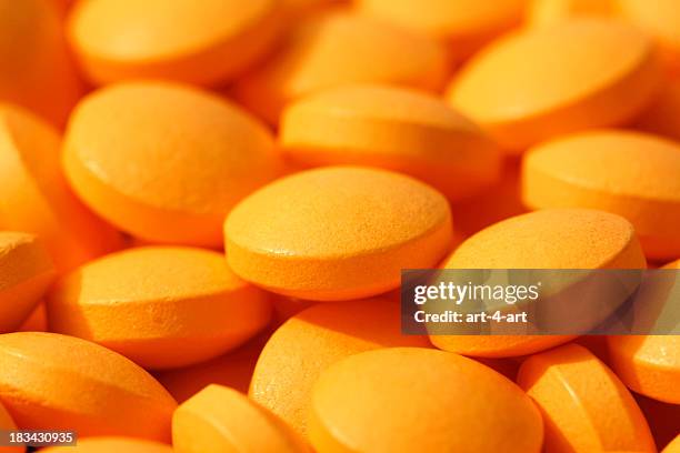 closeup of orange pills - pill background stock pictures, royalty-free photos & images