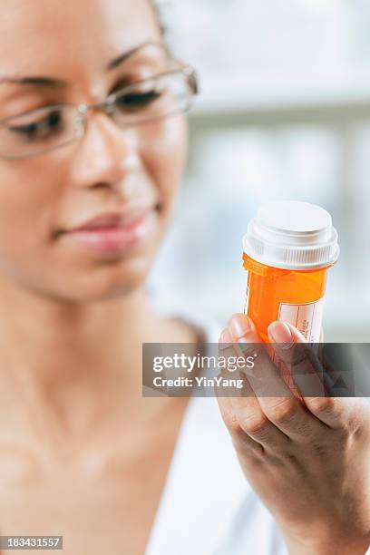 black woman patient holding prescription drugs, looking at pill medication - prescription medicine bottle stock pictures, royalty-free photos & images