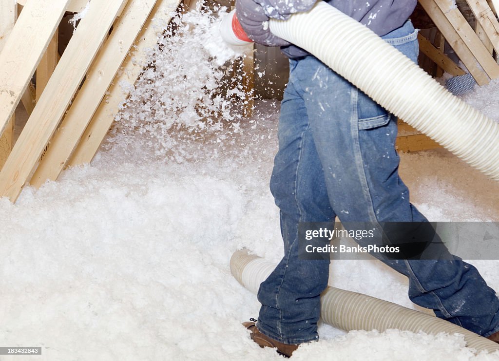 Arbeiter sprühen geschäumten aus Fiberglas-Isolierung zwischen Dachgeschoß Trusses