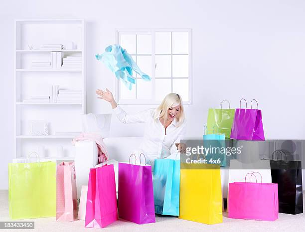 woman in living room opening presents surrounded by gift bags - surrounding stock pictures, royalty-free photos & images