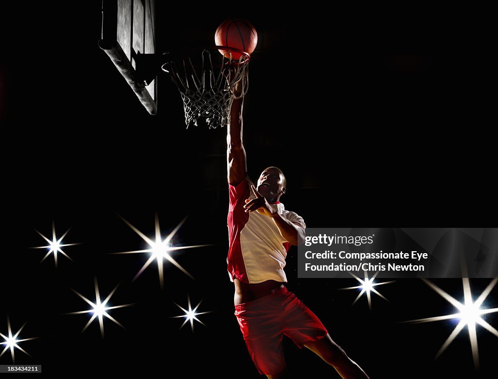 Basketball player dunking basketball on court