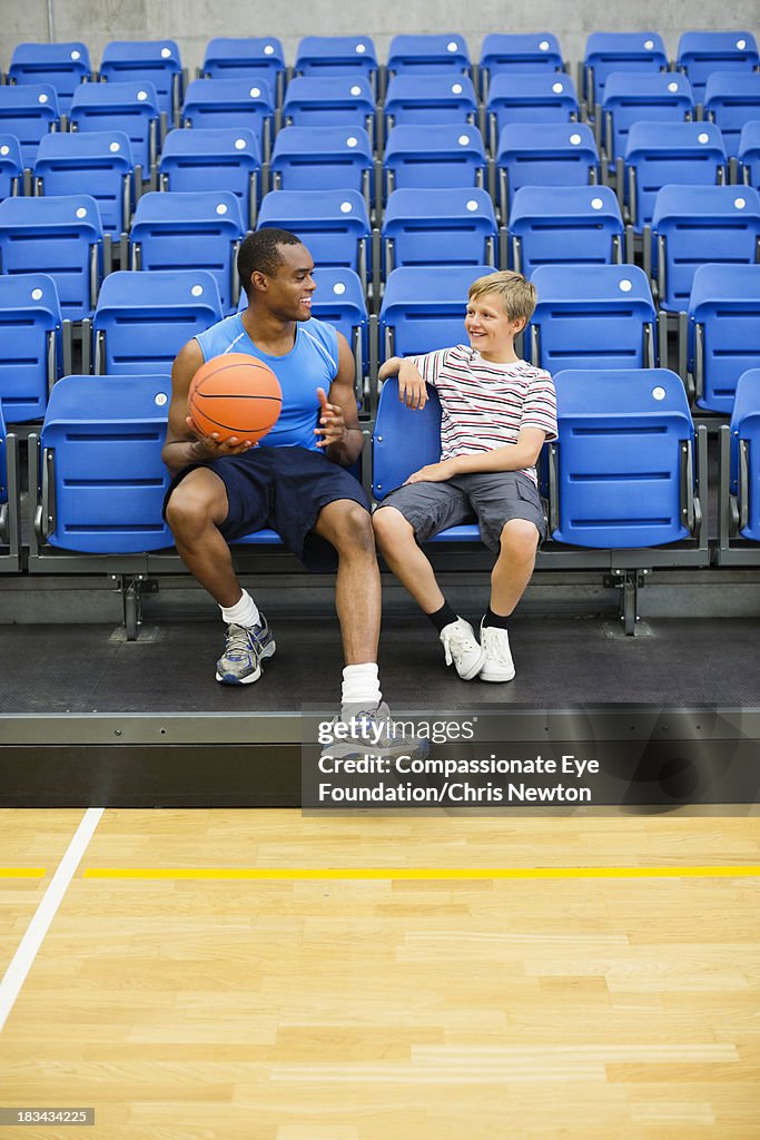 Boy (10-11) sitting in gym with basketball coach