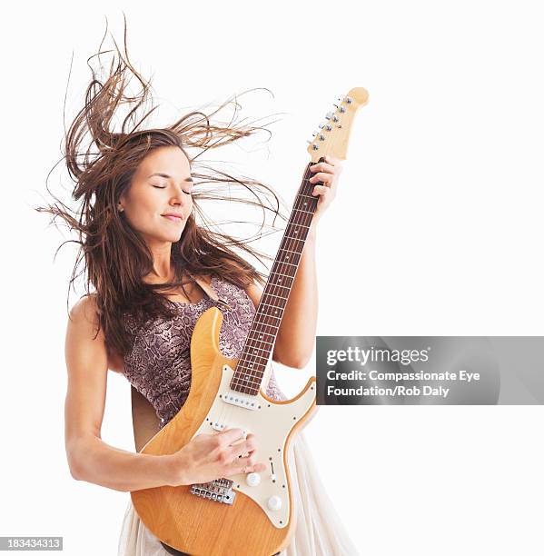 woman playing electric guitar with hair blowing - instrumento de cuerdas fotografías e imágenes de stock