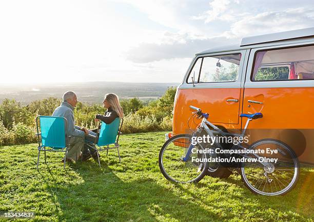 couple sitting in deck chairs by camper van - vintage bicycle stock pictures, royalty-free photos & images