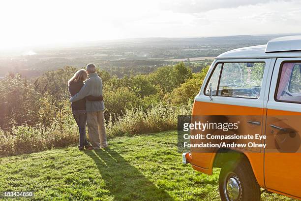 rear view of couple hugging by camper van - take a vintage summer road trip stock pictures, royalty-free photos & images