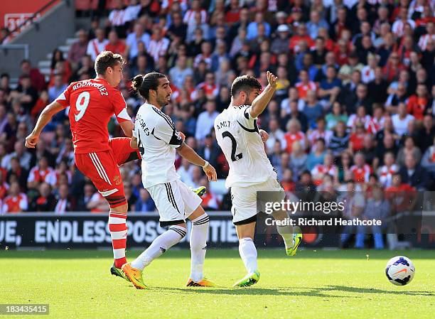 Jay Rodriguez of Southampton shoots past Chico Flores and Jordi Amat of Swansea City to score their second goal during the Barclays Premier League...