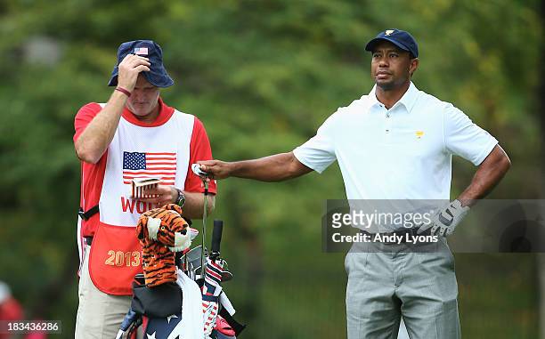 Tiger Woods of the U.S. Team pulls a club on the second hole as his caddie Joe LaCava looks during the Day Four Singles Matches at the Muirfield...