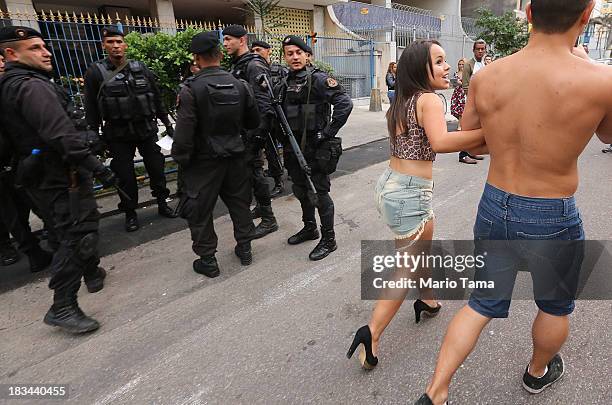 People walk past as military forces wait to start a 'pacification' operation in the nearby favela complex of Lins de Vasconcelos, in the North Zone,...