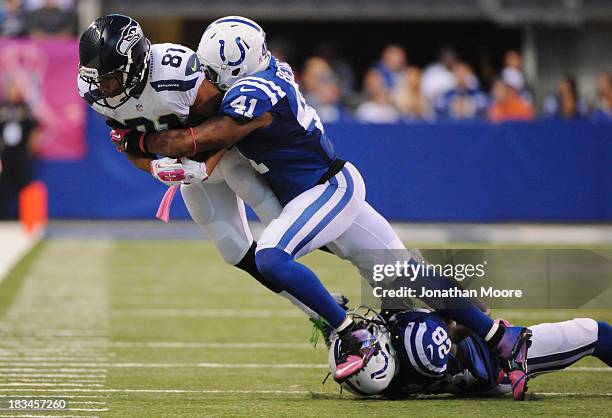 Golden Tate of the Seattle Seahawks is taken down by Antoine Bethea and Greg Toler of the Indianapolis Colts during a game at Lucas Oil Stadium on...