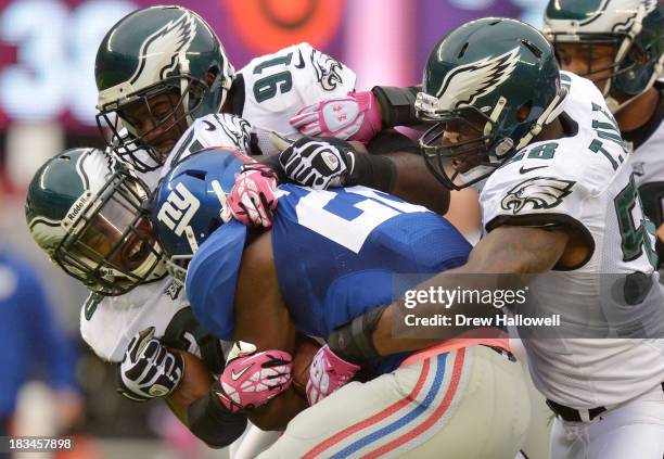 David Wilson of the New York Giants gets tackled by Earl Wolff, Fletcher Cox and Trent Cole of the Philadelphia Eagles at MetLife Stadium on October...