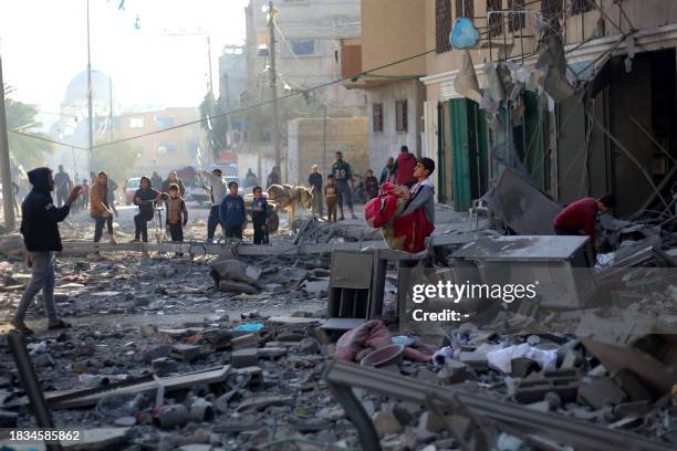 Young boy tries to salvage some objects amid the rubble of a building hit by an Israeli strike in Khan Yunis in the southern Gaza Strip on December...