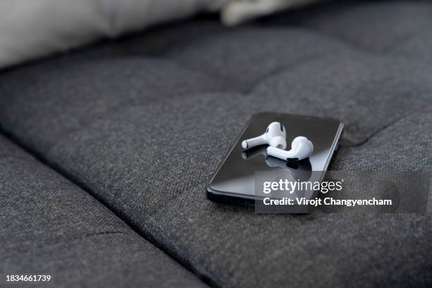 smartphone with wireless bluetooth headphones - bluetooth photos et images de collection