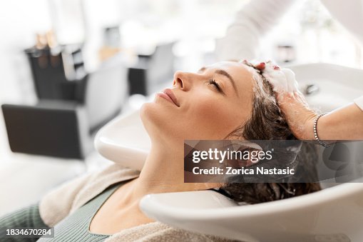 Young Woman Relaxes as Hairdresser Washes Her Hair Young Woman Relaxes as Hairdresser Washes Her Hair
