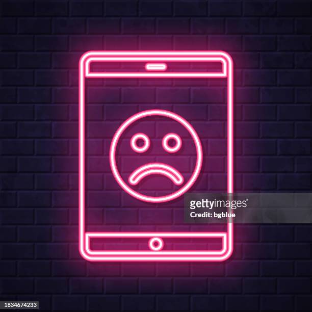 ilustrações, clipart, desenhos animados e ícones de tablet pc com emoji triste. ícone de néon brilhante no fundo da parede de tijolo - disappointing phone