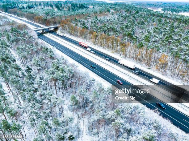 highway through a snowy forest landscape seen from above - car underside stock pictures, royalty-free photos & images