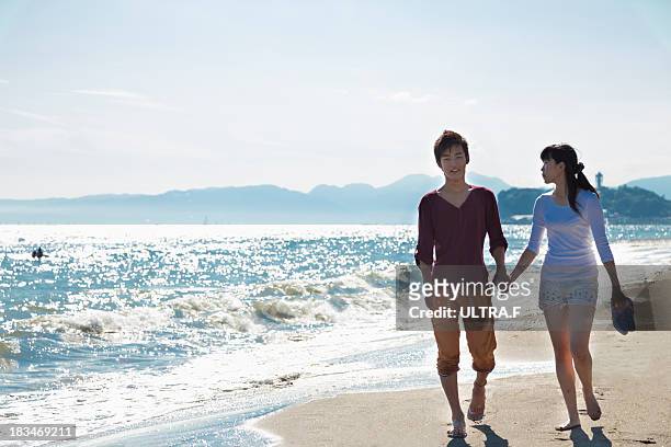 young couple walking on the beach - kamakura stock pictures, royalty-free photos & images
