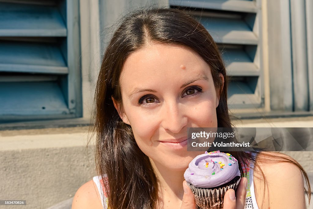 Woman about to eat a purple chocolate cupcake