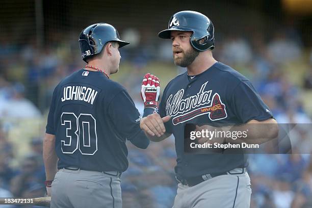 Evan Gattis of the Atlanta Braves scores a run in the first inning and celebrates with Elliot Johnson against the Los Angeles Dodgers during Game...