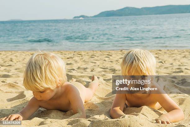 Young identical twin blonde boys lying on a beach