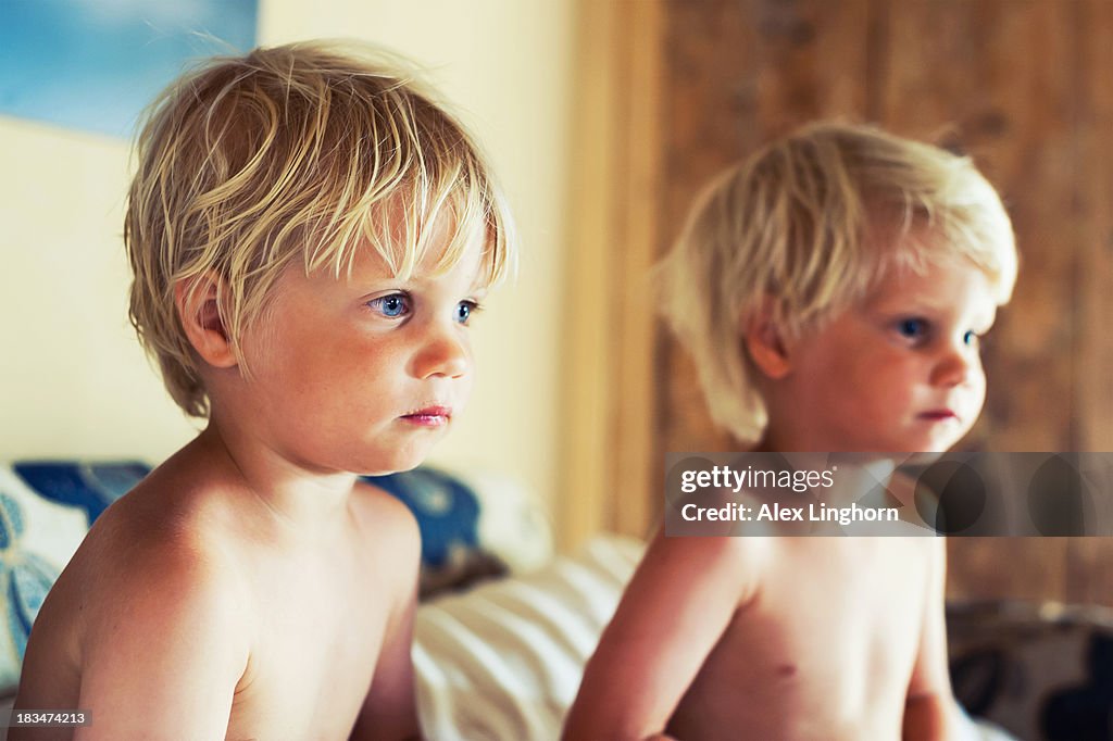 Identical twin blonde boys watching TV