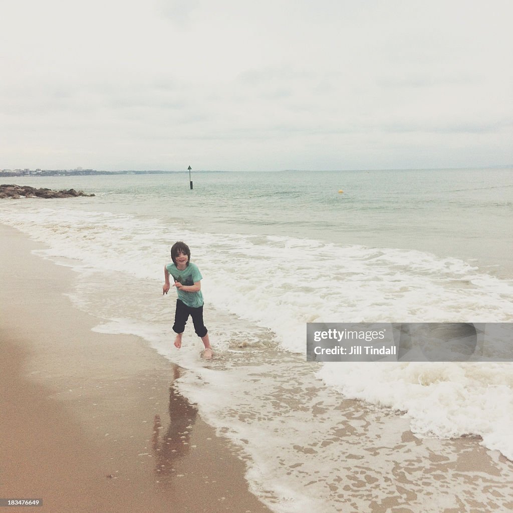 Boy running out of waves, Sandbanks beach, Dorset