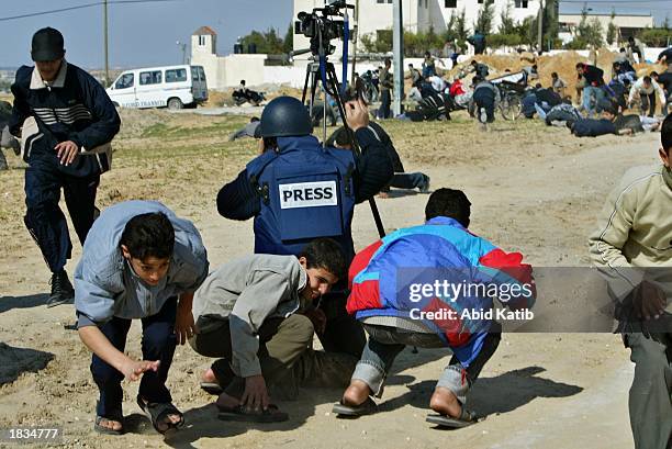 Palestinians and a television cameraman take cover as an Israeli tank opens fire during clashes March 7, 2003 in Beit Lahyea in the Gaza Strip. About...