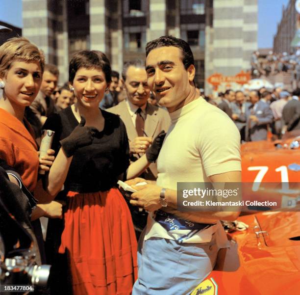 Ferrari team leader Eugenio Castellotti chats with two ladies during scrutineering in the Piazza Vittoria in Brescia, Italy, before the start of the...