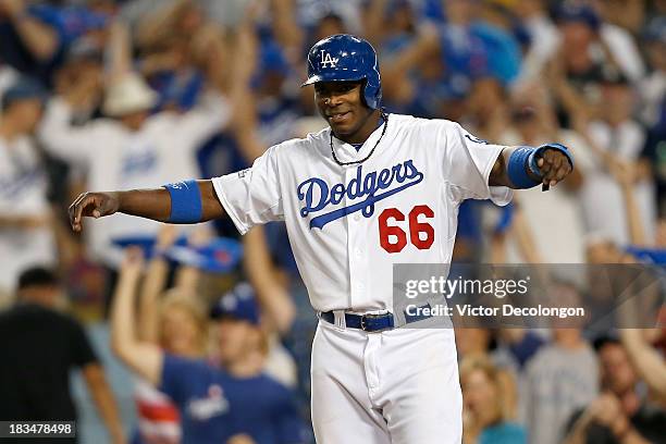 Yasiel Puig of the Los Angeles Dodgers waits for Juan Uribe to come home after Uribe hits a two-run home run in the fourth inning against the Atlanta...