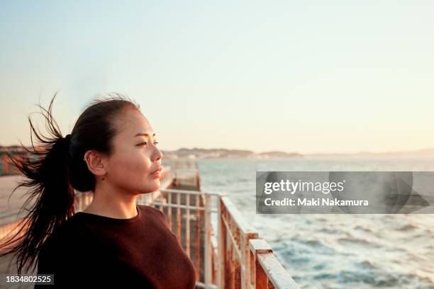 portrait of a young woman basking in the morning sun. - female looking away from camera serious thinking outside natural stock-fotos und bilder