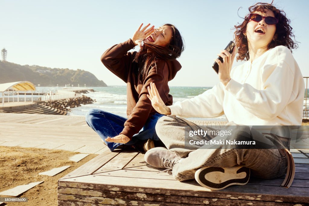 Young woman singing along to music with her cell phone in a park.