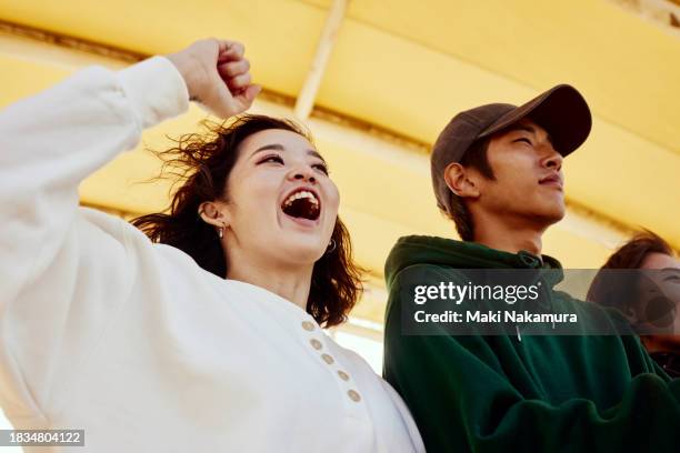 young people cheering for their friends in the audience. - incoraggiamento foto e immagini stock