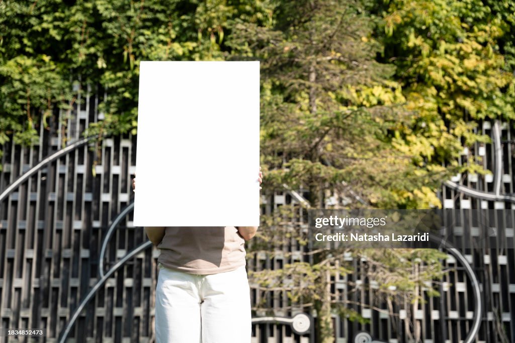 The girl is holding a blank sheet, a poster, and a free space for inscriptions