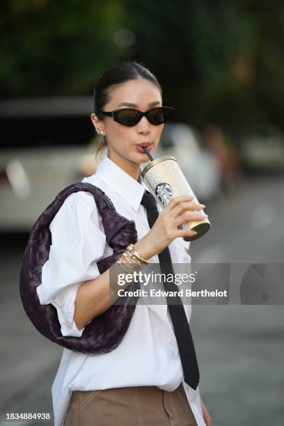 Heart Evangelista wears earrings, sunglasses, golden bracelet from Cartier, a white long shirt from Prada, a black tie from Valentino, a purple woven...