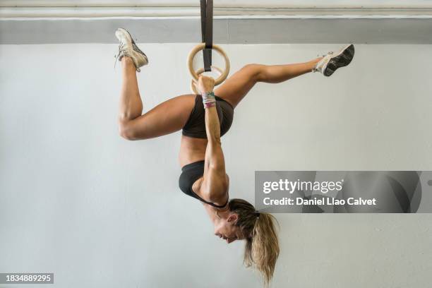 fitness woman training using gymnastic rings in her garage - turnringe-turngerät stock-fotos und bilder