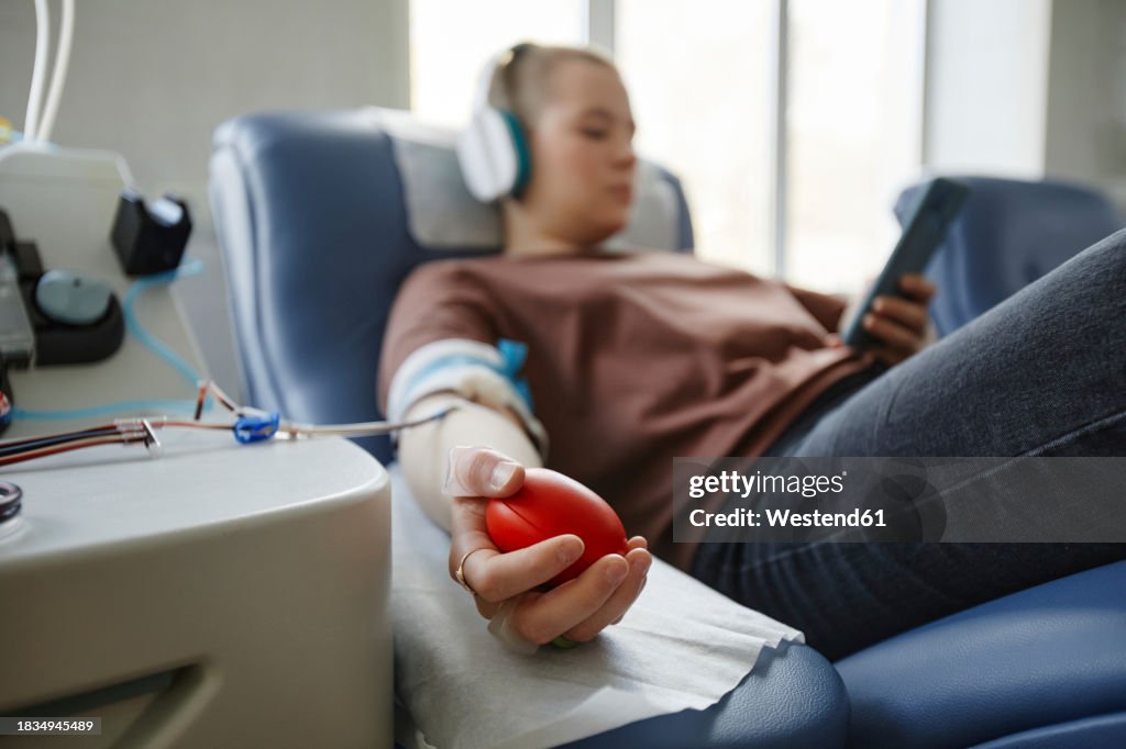 Hand of woman holding soft ball lying on couch at blood donation center