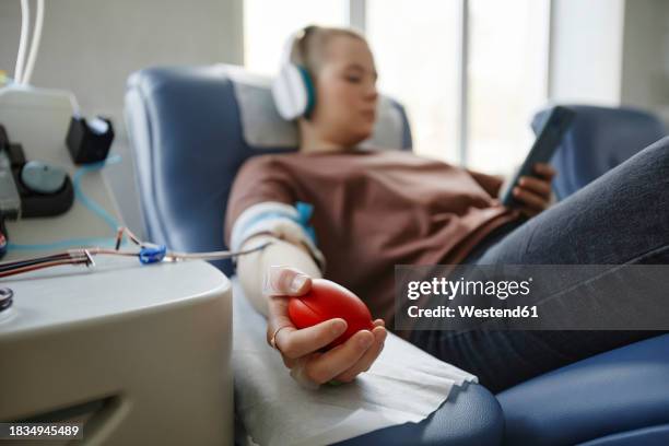 hand of woman holding soft ball lying on couch at blood donation center - blutspende stock-fotos und bilder